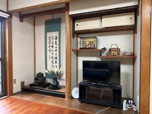 a living room with a flat screen tv and shelves at Yuririan in Kyoto