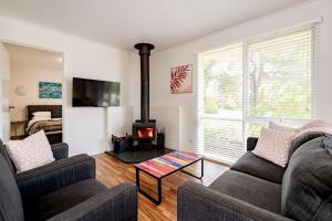a living room with two couches and a fireplace at Bells Beach Cottages in Bellbrae