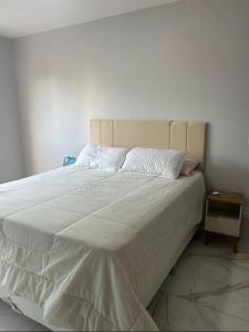 - un lit avec un couvre-lit blanc et une table de chevet dans l'établissement Apartamento com 2 quartos no coração de Brasília, à Brasilia