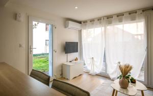 a living room with a table and a large window at Le Cocon Ruthénois - Climatisation, Wifi, Netflix & Jardin in Rodez