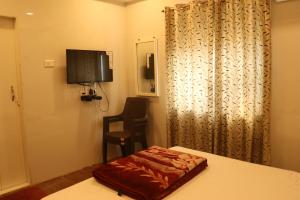 潘韦尔Hotel Geetanjali St Bus Stand Panvel的一间有床、电视和桌子的房间