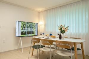 a dining room with a table and chairs and a tv at Songnae Forestay in Bucheon