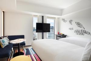 a white bedroom with a bed and a tv at Aloft Tokyo Ginza in Tokyo