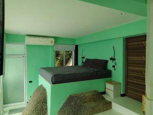 ein Schlafzimmer mit grünen Wänden und einem Bett mit Fenster in der Unterkunft Blue and green apartments in Ban Nua