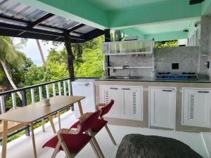 eine Küche mit einem Tisch und Stühlen auf dem Balkon in der Unterkunft Blue and green apartments in Ban Nua