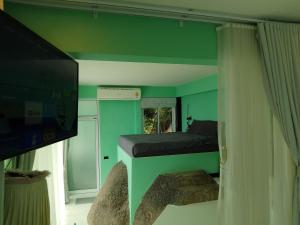 Zimmer mit einem grünen Zimmer mit einem Bett und einem TV in der Unterkunft Blue and green apartments in Ban Nua