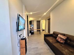 a living room with a couch and a flat screen tv at The Modern A27 Hua-Hin Private Poolvilla from beach 3km in Hua Hin