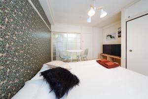 een slaapkamer met een wit bed en een tafel met stoelen bij Kimura House in Tokyo