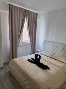 a black ribbon laying on a bed in a bedroom at Luxury Daniel Apartament Residence Militari in Roşu
