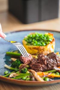 a plate of food with meat and vegetables with a fork at Hotel Akwawit in Leszno +92 photos