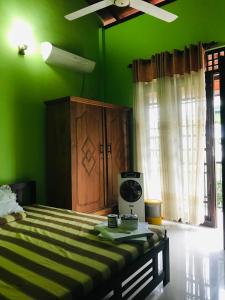 - une chambre verte avec un lit et un mur vert dans l'établissement Matara Heritage Home - Local Family Stay, à Matara