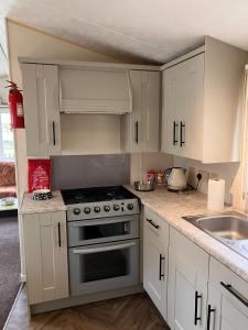 a kitchen with white cabinets and a stove top oven at Mersea Island at Lazeeedays in Colchester