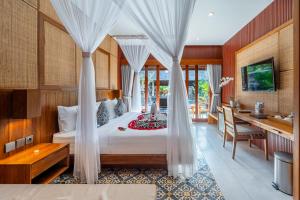 a bedroom with a bed with curtains and a desk at Puri Andong Villa in Ubud