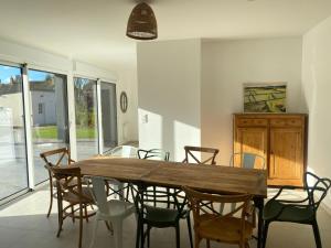 a dining room with a wooden table and chairs at Maison Origines - Escapade au vert in Heudicourt