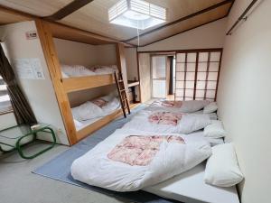 a room with three bunk beds in it at AKANE Hostel あかね天然温泉旅館 in Yuzawa