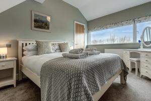 Un dormitorio con una cama y un escritorio y una ventana. en Merlin House at Lower Mill Estate A gorgeous home with lake access, air conditioning and luxury spa access, en Somerford Keynes 30 fotos más