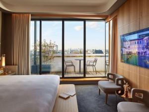 pokój hotelowy z łóżkiem i dużym oknem w obiekcie Domaine de la Reine Margot Paris-Issy - MGallery Collection w mieście Issy-les-Moulineaux