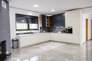 a large kitchen with white cabinets and a fireplace at Villa Bosanska Zvijezda in Vlasic