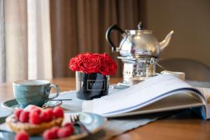 a table with a book and a red rose in a mug at Antares Spiekerooger Gästehaus-Sonnengartenterrasse West - Wohnung 8 in Spiekeroog