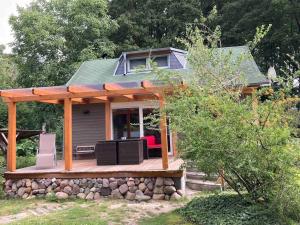 a small house with a wooden deck with a porch at Behagliches Cottage am See in Fürstenberg-Havel