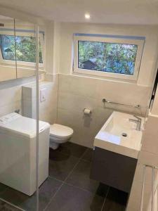 a bathroom with a toilet and a sink and a window at Behagliches Cottage am See in Fürstenberg-Havel +13 photos