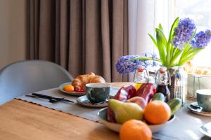 a table with fruit and coffee cups and flowers at Antares Spiekerooger Gästehaus-Sonnengartenterrasse West - Wohnung 2 in Spiekeroog