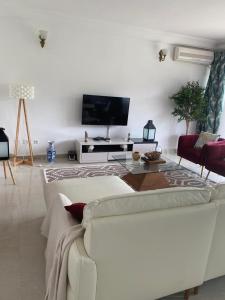 a living room with a white couch and a tv at Residence La Marina in Yaoundé