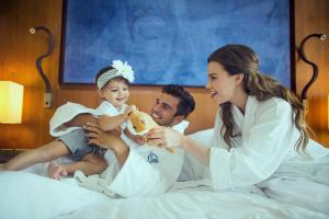 a man and woman sitting on a bed with a baby at Yas Island Rotana Abu Dhabi in Abu Dhabi