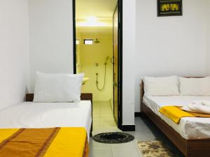 two beds in a room with a shower at Dream View Hotel in Polonnaruwa
