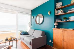 a living room with a couch and a blue wall at Le Rayon Vert - Vue sur l'aiguille et garage priv in Étretat
