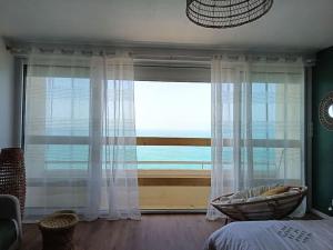 a bedroom with a large window with a view of the ocean at Le Rayon Vert - Vue sur l'aiguille et garage priv in Étretat