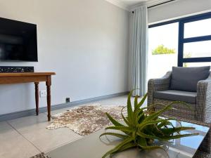 a living room with a table and a chair and a plant at DIE Huis House in Wilderness