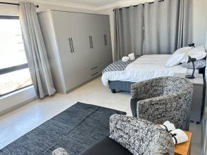 a bedroom with a bed and a chair and a couch at DIE Huis House in Wilderness