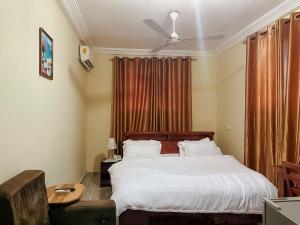 KoforiduaにあるSenalli Hotelのベッドルーム1室(ベッド1台、テーブル、シーリングファン付) +11枚の写真