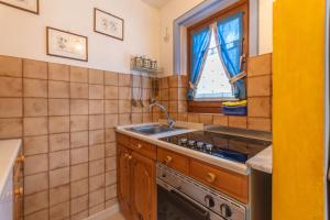 a kitchen with a sink and a stove and a window at Casa Riccardo in Soraga