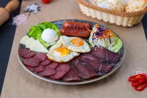 a plate of breakfast food with eggs meat and vegetables at Alegria Rooms Sarajevo in Ilijaš