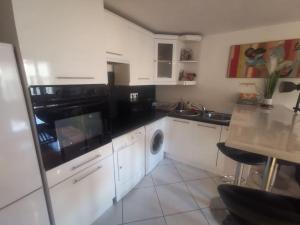 une cuisine avec des armoires blanches et des appareils noirs dans l'établissement Duplex House Paris-CDG-Astérix, à Orry-la-Ville