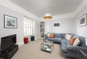 a living room with a blue couch and a tv at Henscath House in Helston