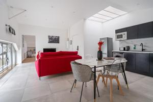 een woonkamer met een rode bank en een tafel bij Loft ROSALIE - Le Méridien #Parking #Lave-linge #Clim #Netflix in Charbonnières-les-Bains