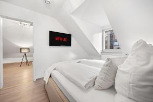 a white bedroom with a bed and a tv on the wall at Malu Rooms - im Stadtzentrum, SmartTV, Netflix, 24h Checkin in Ludwigsburg