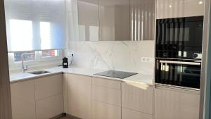 a kitchen with white cabinets and a black microwave at CHAPITELES Catedral in Burgos +25 photos