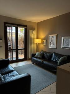 a living room with a black couch and a window at "La Casa di Gio" Appartamento con giardino e ingresso privato in Reggio Emilia