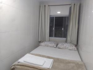 a small bed in a room with a window at kitnet 01 preço popular in Brasília