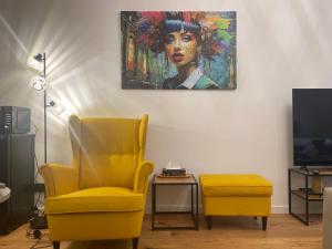uma sala de estar com uma cadeira amarela e um quadro em Silesia Blue2 Apartment - Katowice em Katowice
