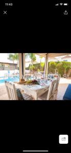 a dining table and chairs with a pool in the background at Villa 4 in Ayia Thekla in Ayia Napa