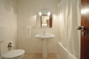 une salle de bain avec un lavabo, des toilettes et un miroir dans l'établissement Paula Bela by Garvetur, à Quarteira 28 autres photos