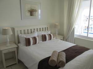 a bedroom with a white bed with pillows and a window at Point Village Accommodation - Stephen in Mossel Bay