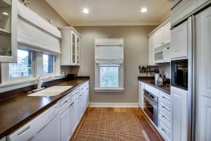 une cuisine avec des armoires blanches, un évier et une fenêtre dans l'établissement Beachy Bungalow, à Santa Rosa Beach