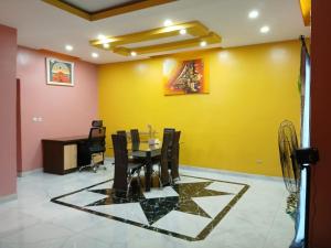 a dining room with a table and a yellow wall at BlueHouseCity in Grand-Bassam