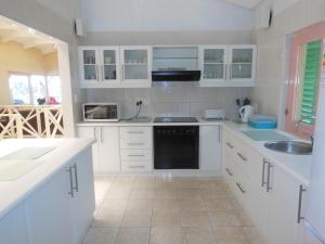 a white kitchen with white cabinets and a sink at The Green Gate in Zinkwazi Beach
